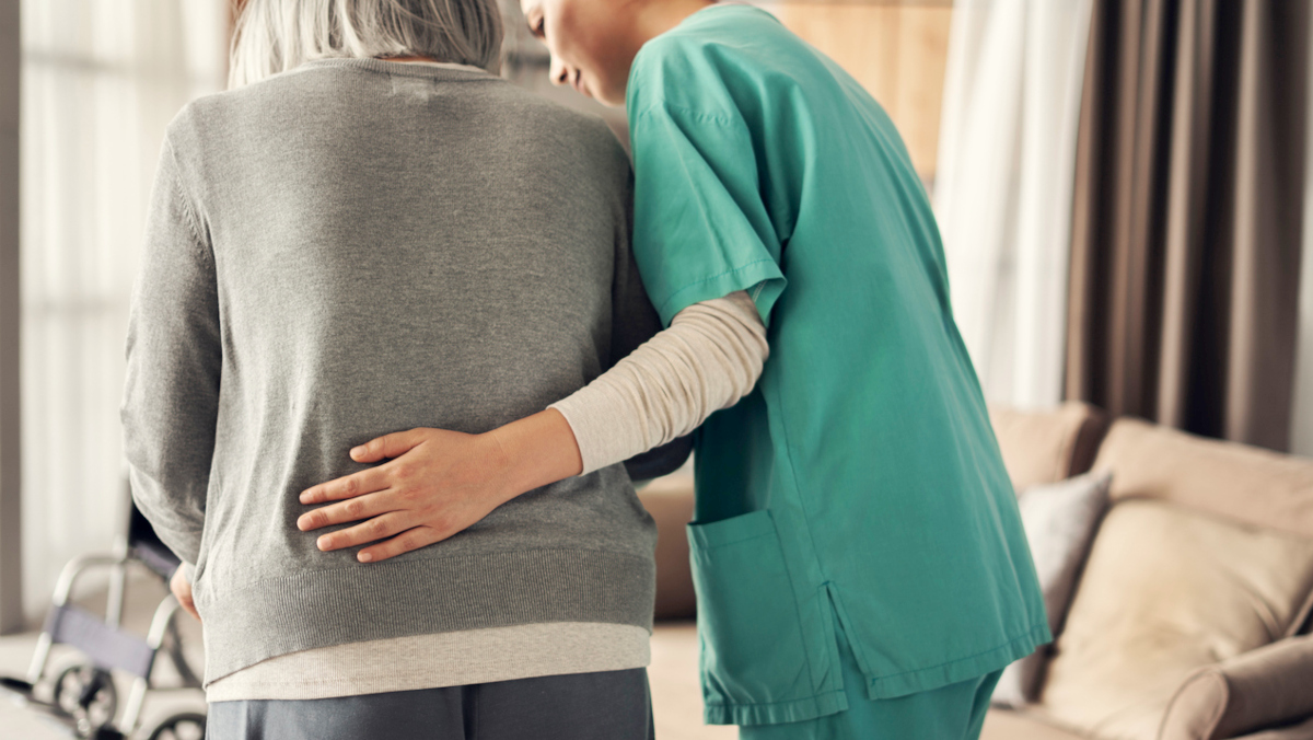 Pflegekraft hilft alter Frau beim Gehen