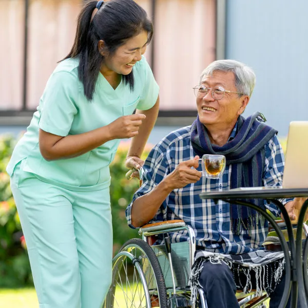 asiatische Pflegekraft Mann im Rollstuhl Freude