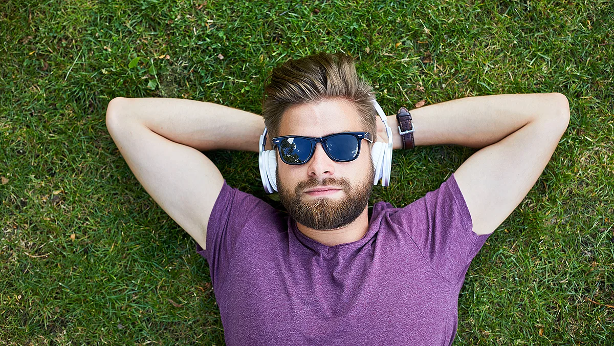 Mann im Gras mit Kopfhörer Foto iStock Bartek Szewczyk Mann im Gras mit Kopfhörer