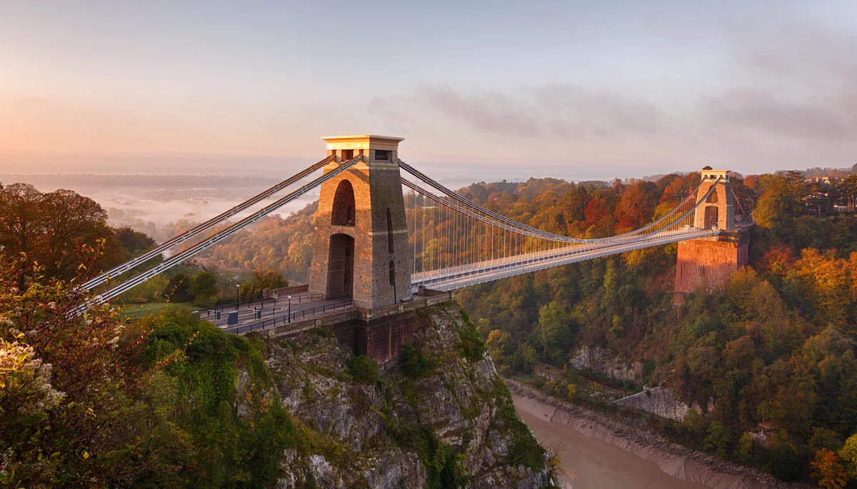 2b96384f958f-iStock-1182089017 Clifton Suspension Bridge on an autumn morning as the sun rises and breaks through the clouds Uk großbritannien