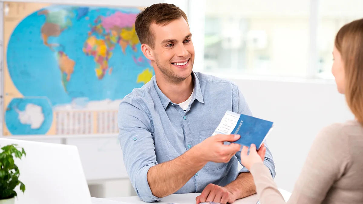Reisebüro Junger Mann am Counter überreicht Ticket Foto iStock Dima Sidelnikov Reisebüro Junger Mann am Counter überreicht Ticket